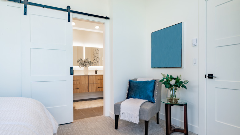 An open wooden barn door leading to a bathroom