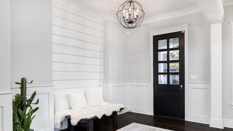 The foyer of a home with white shiplap on the wall above a wooden bench
