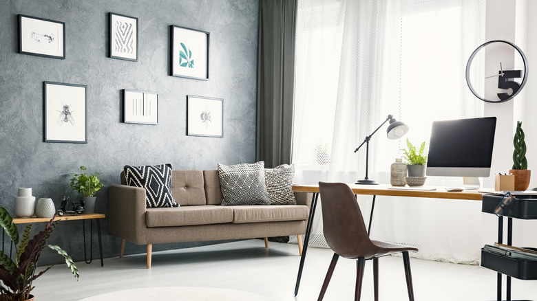 Home office with a a desk, couch, and a large window