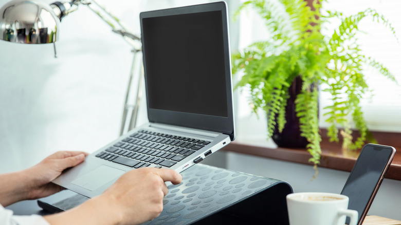 Man's hands sitting a laptop on a stand