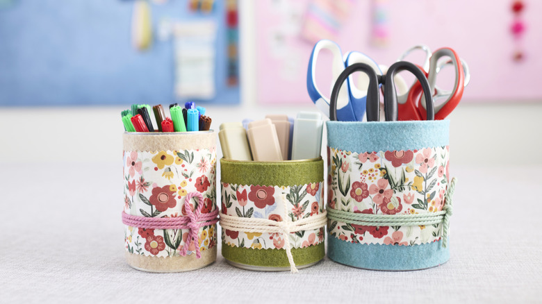 Tin cans with felt and ribbon holding office supplies
