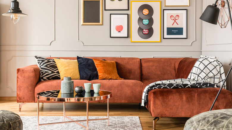 An eclectic living room with an orange velvet sofa and pillows