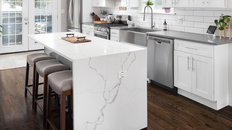 A white kitchen with a waterfall countertop