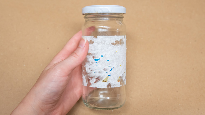person holding jar with partially removed label