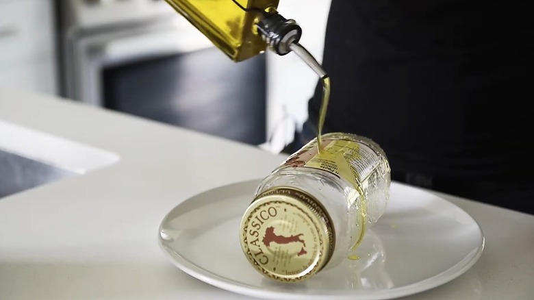 person pouring olive oil on jar sticker