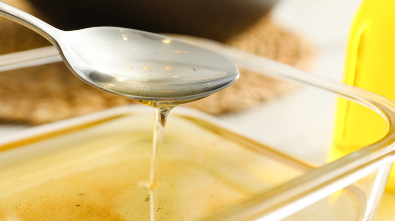 pouring vegetable oil into glass container with spoon