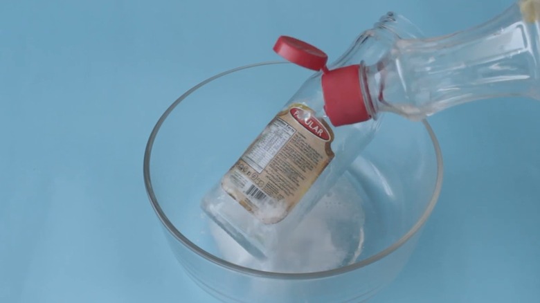 person pouring vinegar onto bottle label