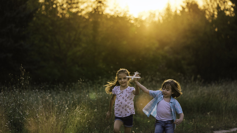 Kids playing in natural-looking area near tall grasses