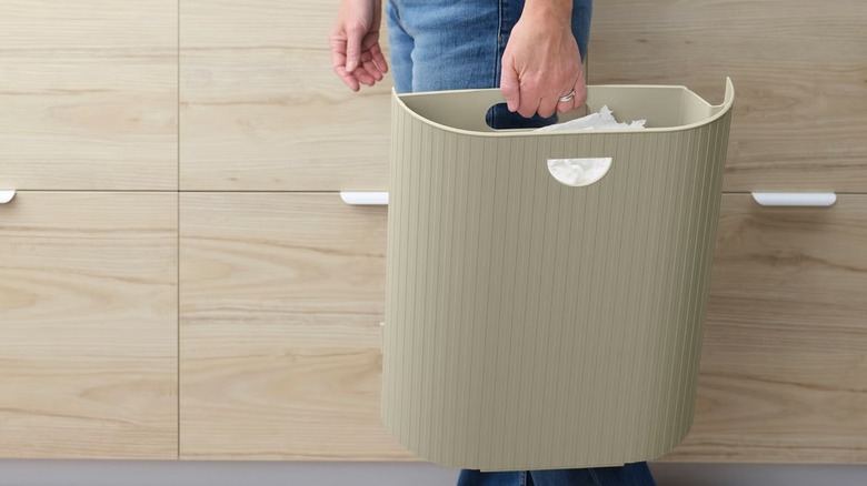 Person carrying GÅRDSBUTIK Bin with lid insert