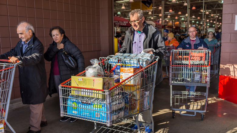 People leaving a Costco with full carts