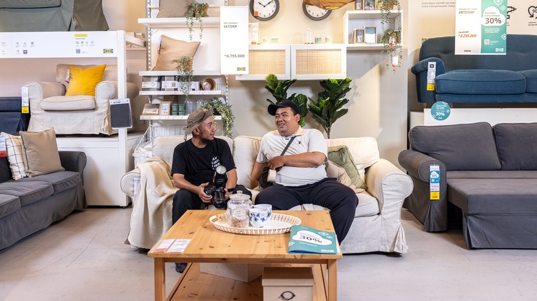Two customers at IKEA sitting on a small white couch in the display area