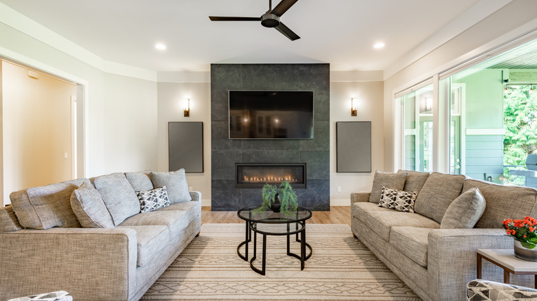 A living room with two gray sofas layered with matte black and gold finishes