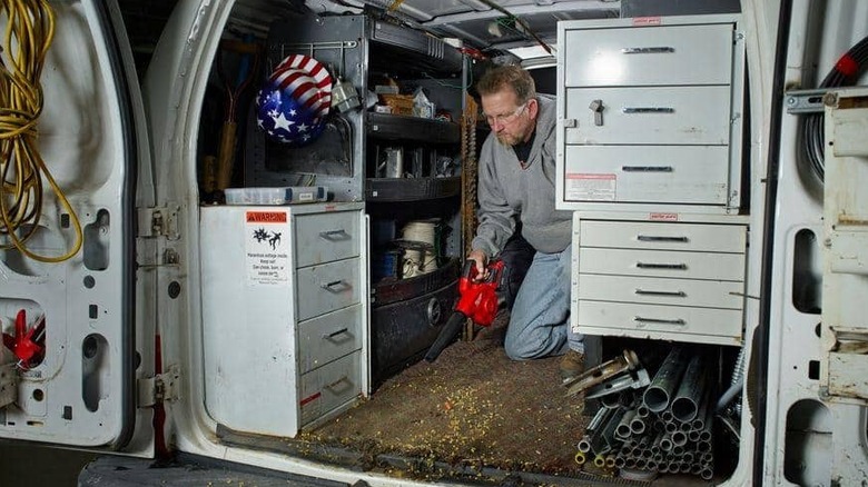 Man using blower to remove sawdust from inside van