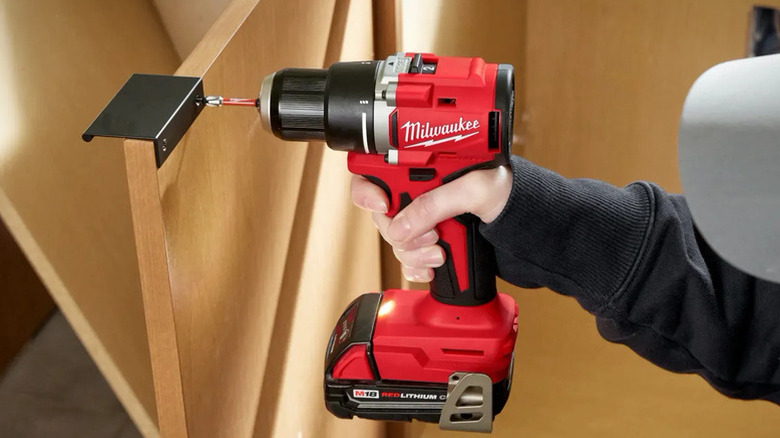 Man drilling pilot hole in wood with compact drill