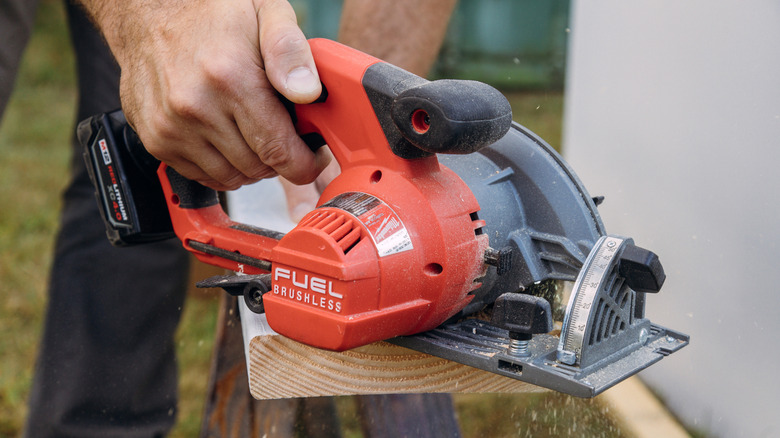 Milwaukee circular saw cutting plank outdoors