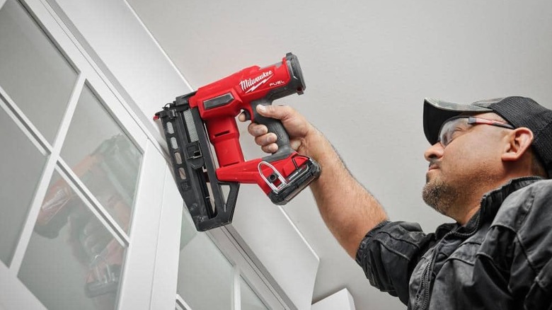 Man stapling window frame with nail gun