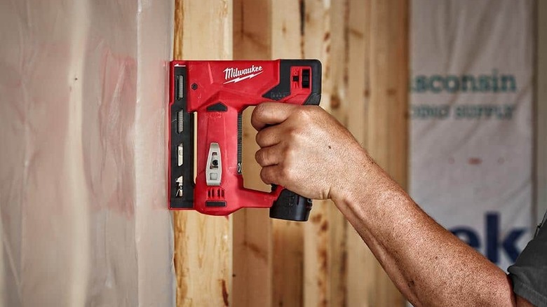 Person using staple gun on framing
