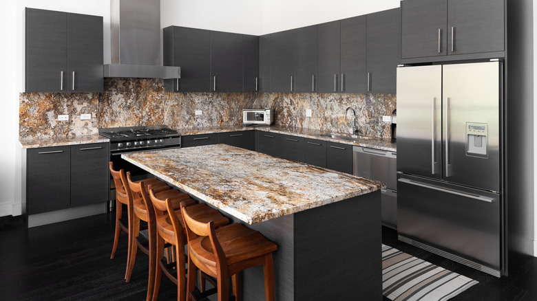 Warm marble countertops in kitchen with black cabinets