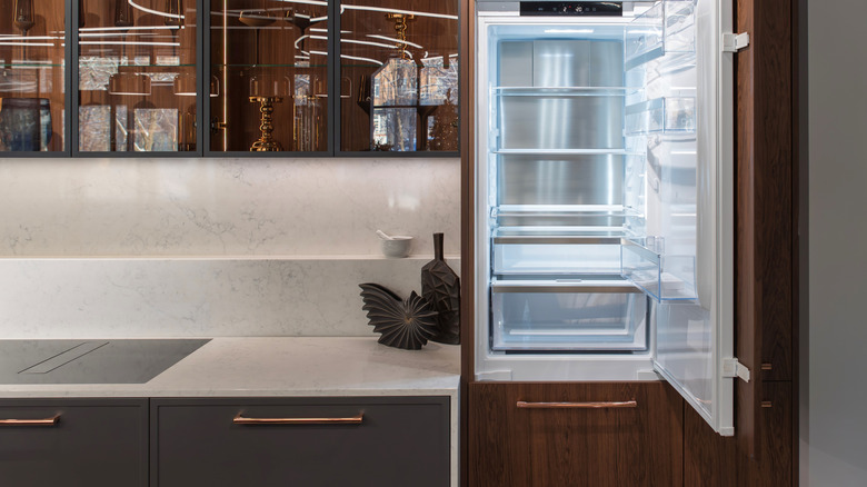 An empty and open refrigerator in a clean modern kitchen beside a clear kitchen countertop