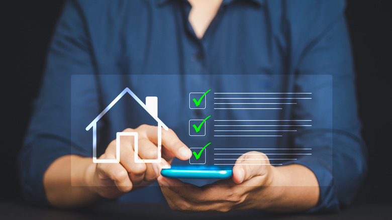 A man looks at a digital list behind a house checklist