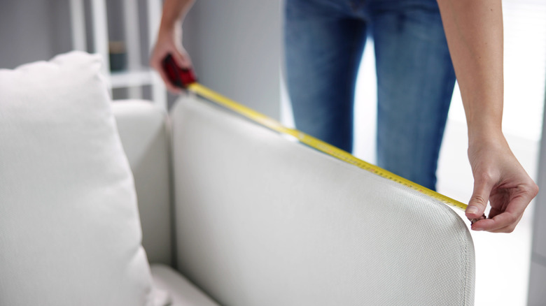 A person measuring the arm of a chair