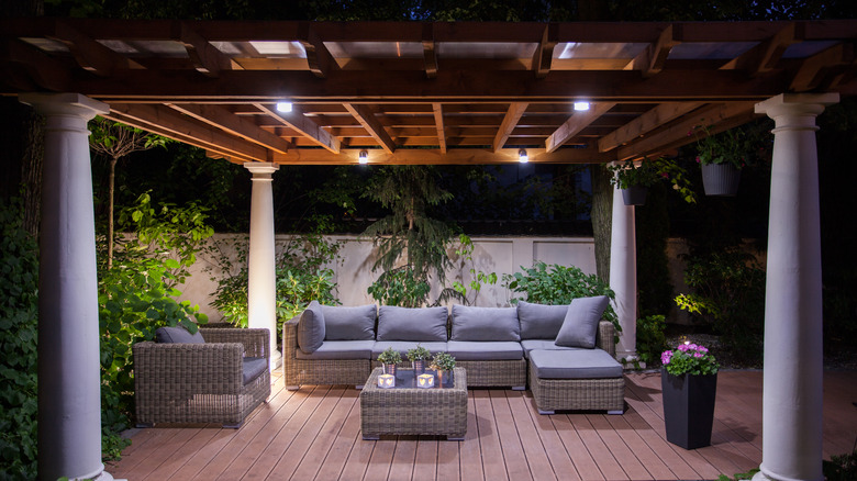 A pergola fitted with cozy lighting and furnished with outdoor seating