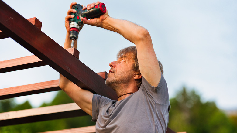 man building a pergola using power tool