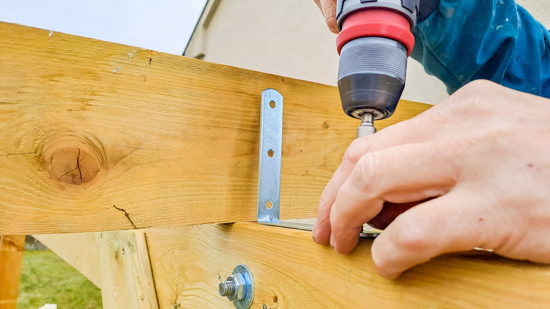 Close up of a person drilling into a timber frame