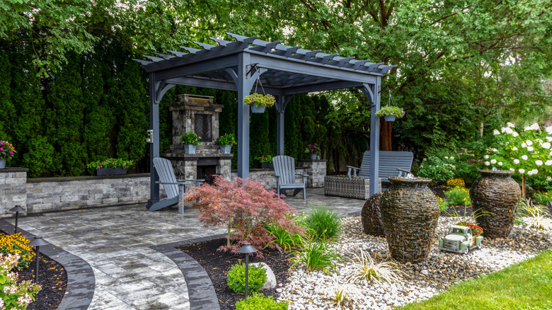 A blue-gray wooden pergola in a well-established, peaceful garden