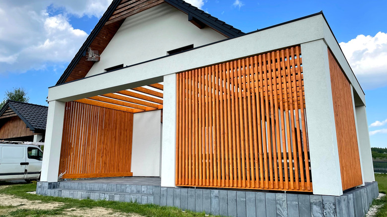 A custom pergola with side walls made from wooden slats