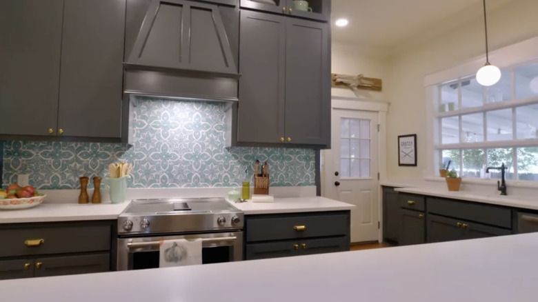 Modern kitchen with dark gray cabinetry and blue tile-patterned wallpaper