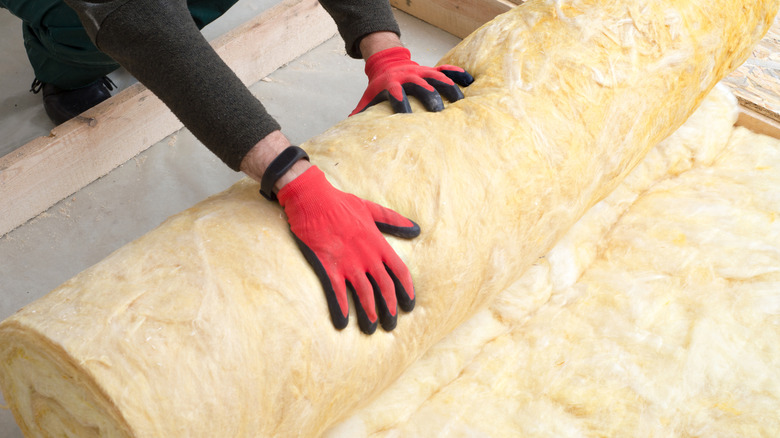 Person rolling out insulation during installation