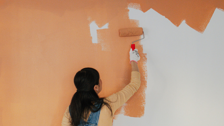 Woman painting a wall orange
