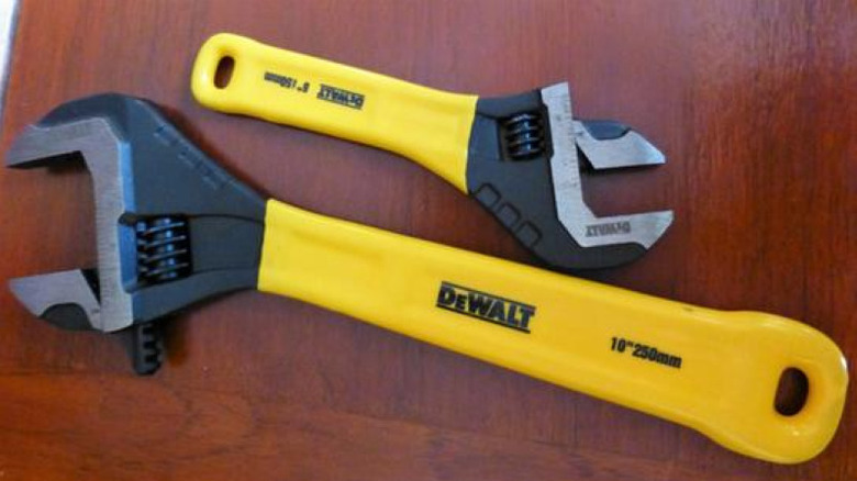 Pair of DeWalt yellow wrenches on glossy red wood surface