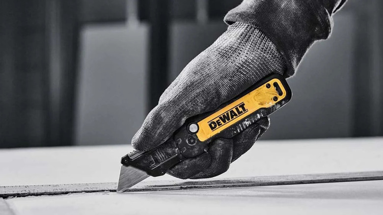 Gloved hand carving surface with DeWalt folding utility knife