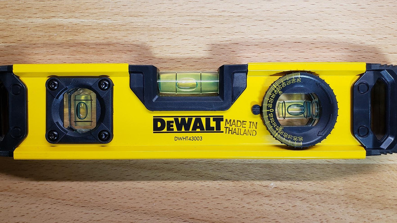 DeWalt torpedo level with three bubble levels on wood surface