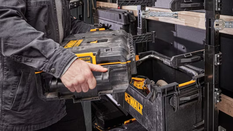 Man holding heavy duty DeWalt toolbox beside other DeWalt branded items