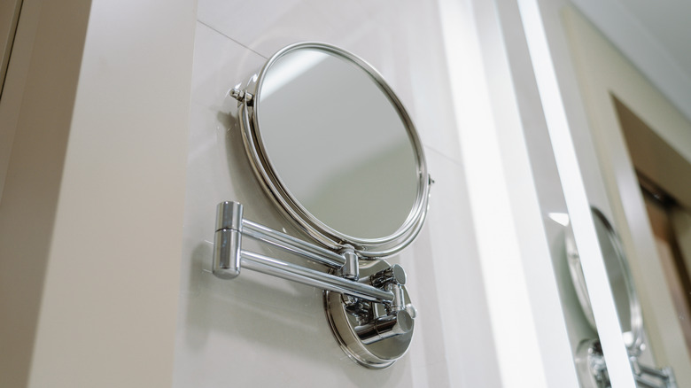 A retractable shaving mirror mounted to a bathroom wall