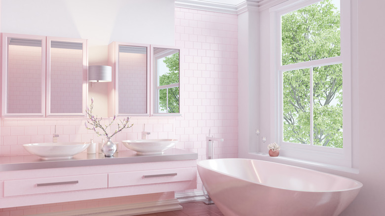 A light pink bathroom with a standing tub and window overlooking a tree
