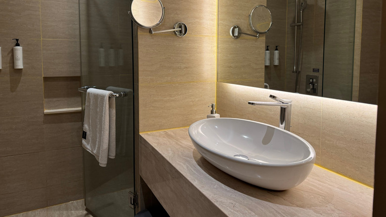 Neutral, warmly lit bathroom with a large vessel sink