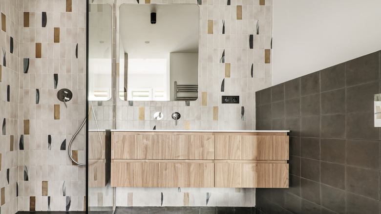 A pale wood bathroom vanity with a plain mirror