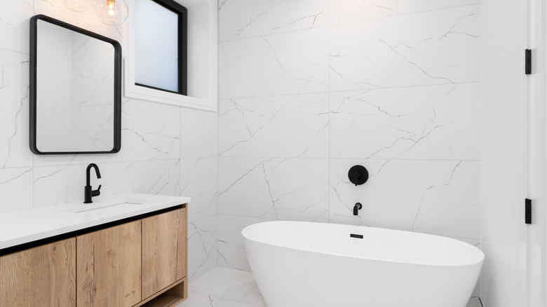 Modern bathroom with a light wood tone vanity and white standing tub