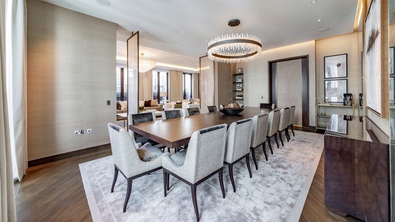 A dining room featuring a sculptural crystal chandelier above a long table