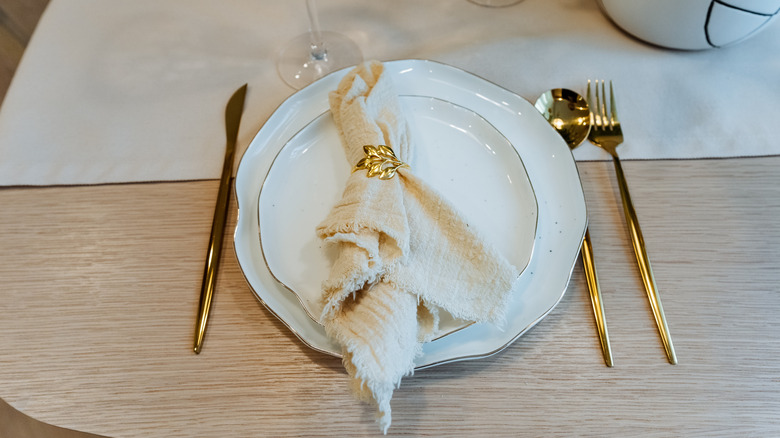 A white place setting with gold flatware