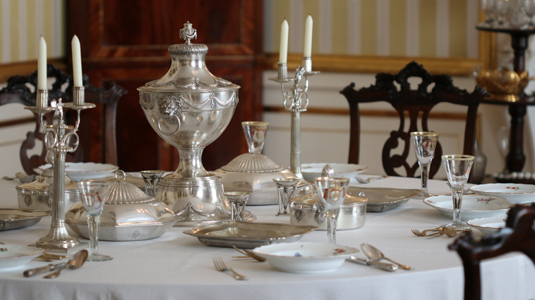 Vintage silver tableware set on a formal dining table with a white tablecloth