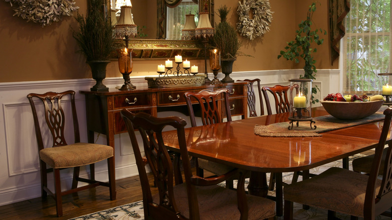 An old-fashioned dining room with a varnished wooden table surrounded by chairs