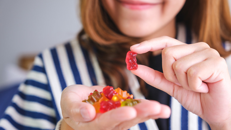 A woman eats gummy bears out of her hand.