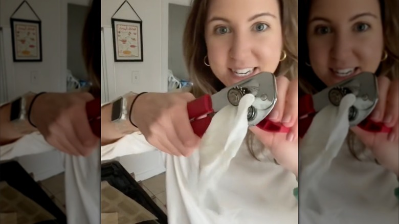 person cleaning a can opener with paper towels