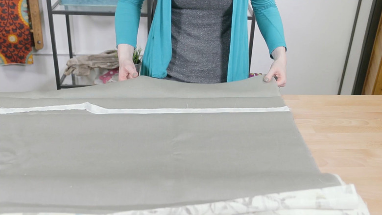 a woman lays weighted drapery tape into the hem of her pleated curtains