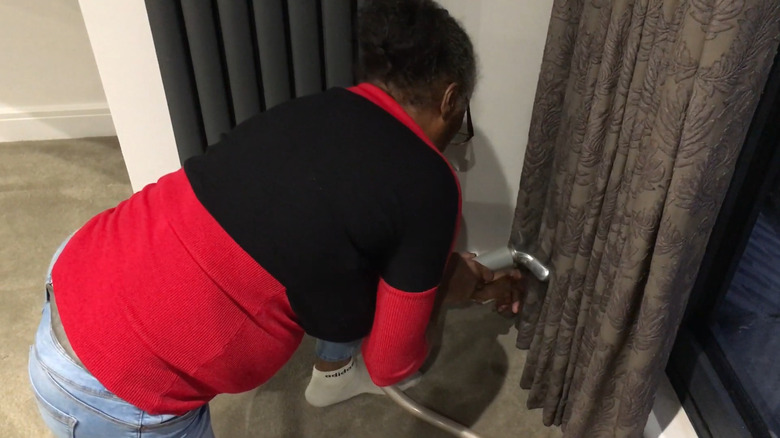 a woman is steaming her pleated curtains before training the pleats